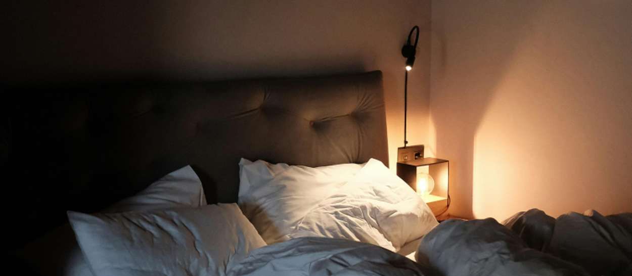 Chambre sombre éclairée par une lampe de chevet, lumière artificielle qui perturbe le sommeil
