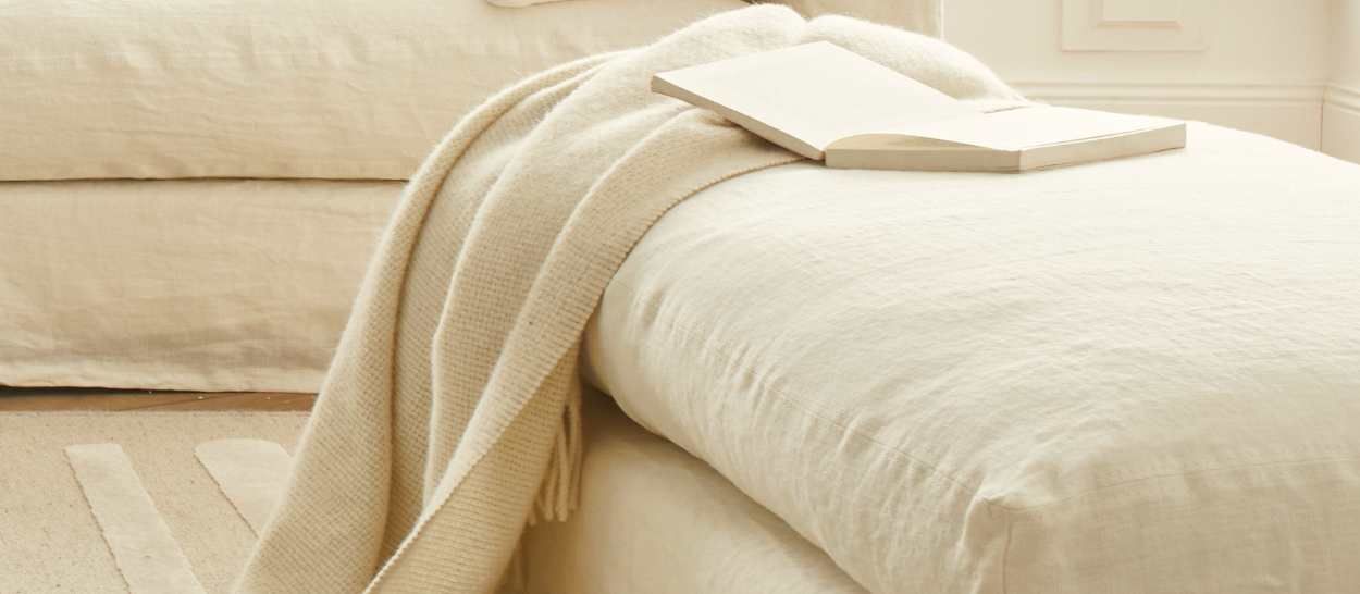 Méridienne en lin naturel avec un plaid et un livre posé, illustrant une assise douce et soutenante pour un coin lecture.