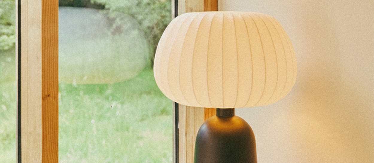 Lampe à lumière douce placée près d’une fenêtre, créant une ambiance apaisante pour un coin lecture.