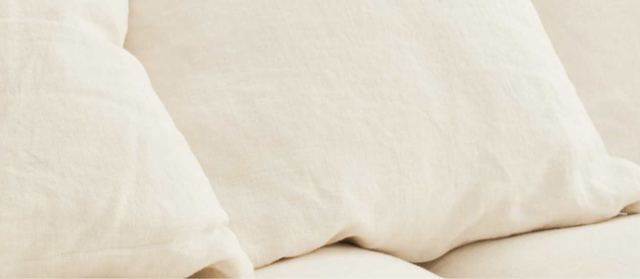 Gros plan sur des coussins en lin naturel, illustrant des matières respirantes pour un coin lecture paisible.