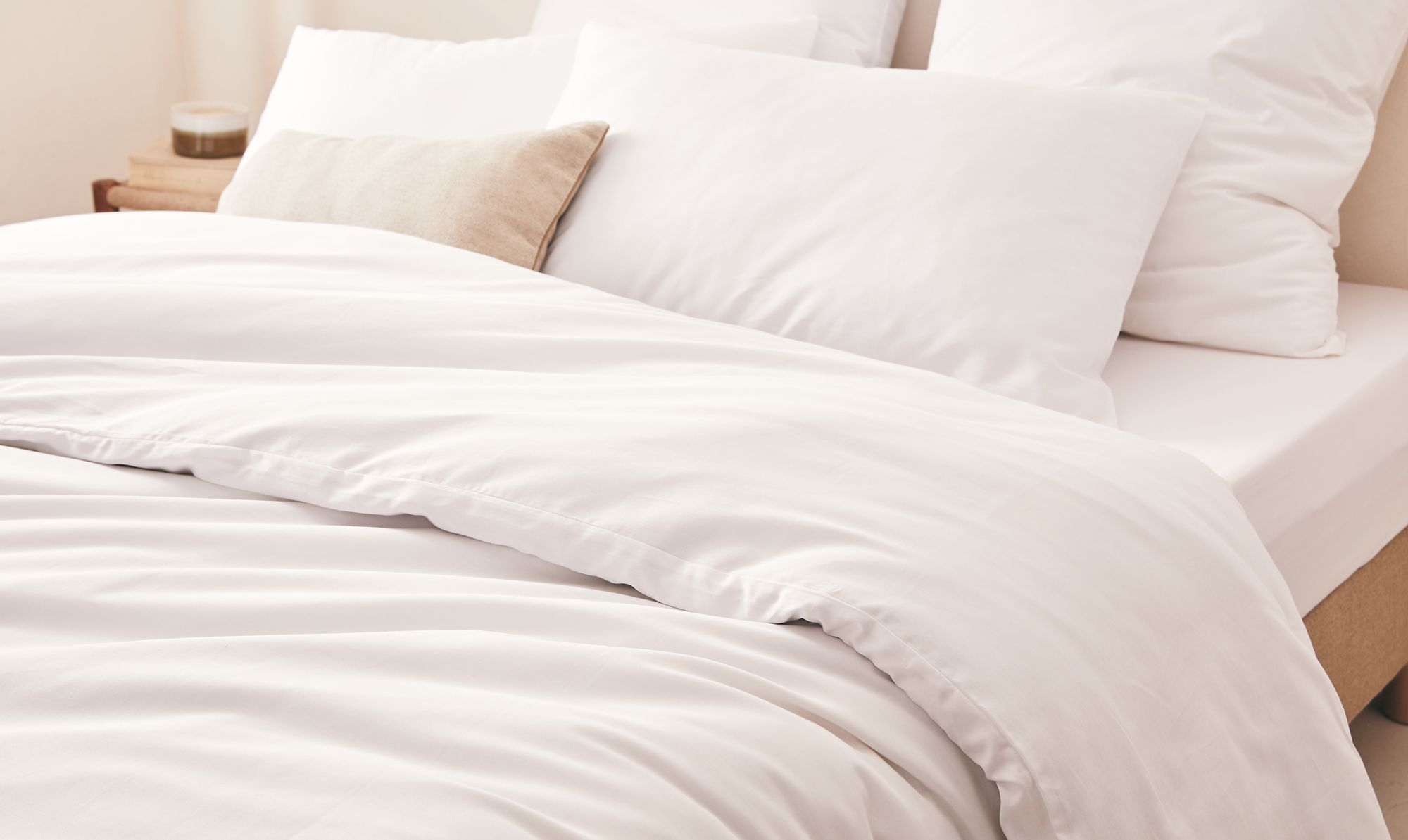 Housse de couette et taies en coton bio ivoire sur matelas avec drap-housse assorti, texture douce et respirante pour une chambre saine.