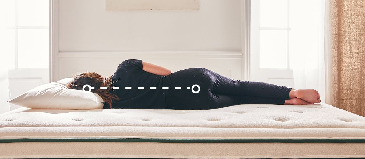 Dormeur allongé sur le côté sur un matelas en latex, ligne en pointillés illustrant l’alignement de la colonne vertébrale.