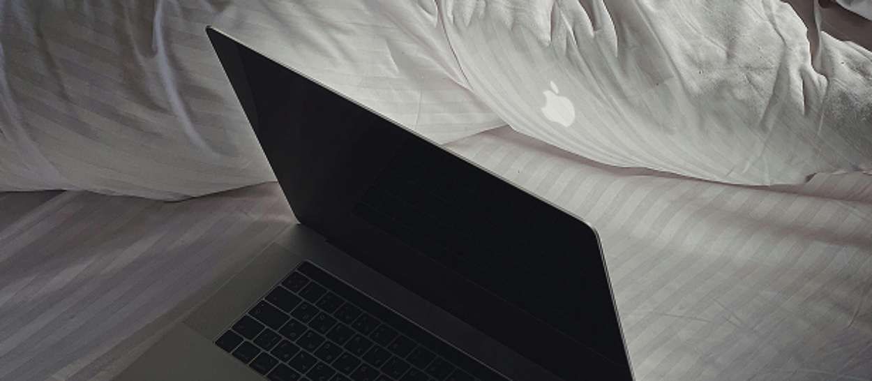 Ordinateur portable posé sur un lit, symbole d'une mauvaise habitude qui perturbe le sommeil