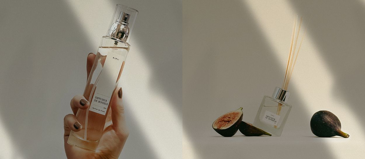 Vaporisateur Kipli tenu en main et diffuseur à bâtonnets posé près de figues mûres, lumière douce et naturelle.