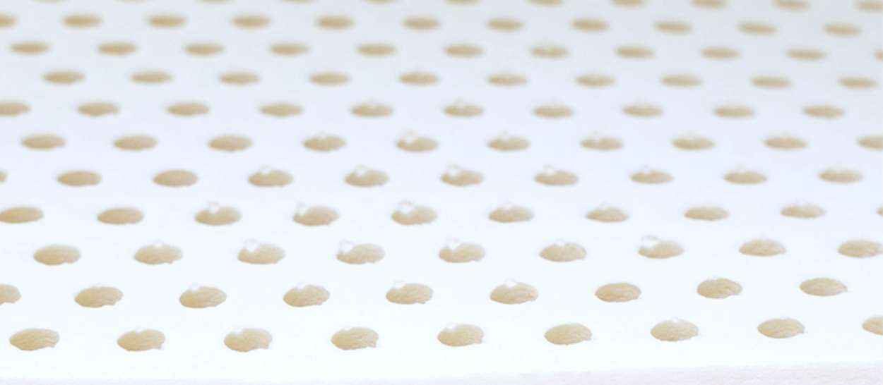 Gros plan sur la structure alvéolaire d’un matelas en latex naturel favorisant la respirabilité