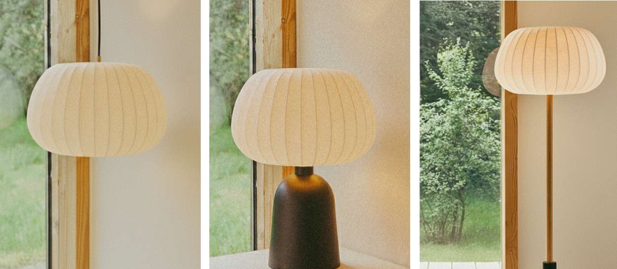 Collection de lampes Hikari avec suspension, lampe à poser et lampadaire au même abat-jour écru devant une grande fenêtre