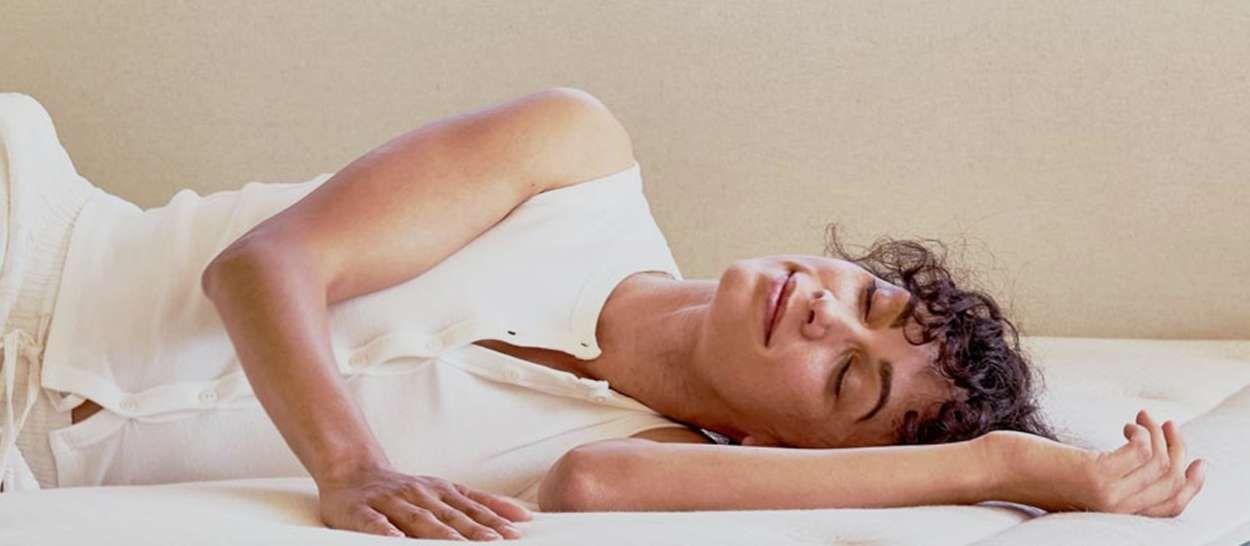 Femme allongée sur un matelas en latex naturel Kipli, visage détendu après une nuit réparatrice