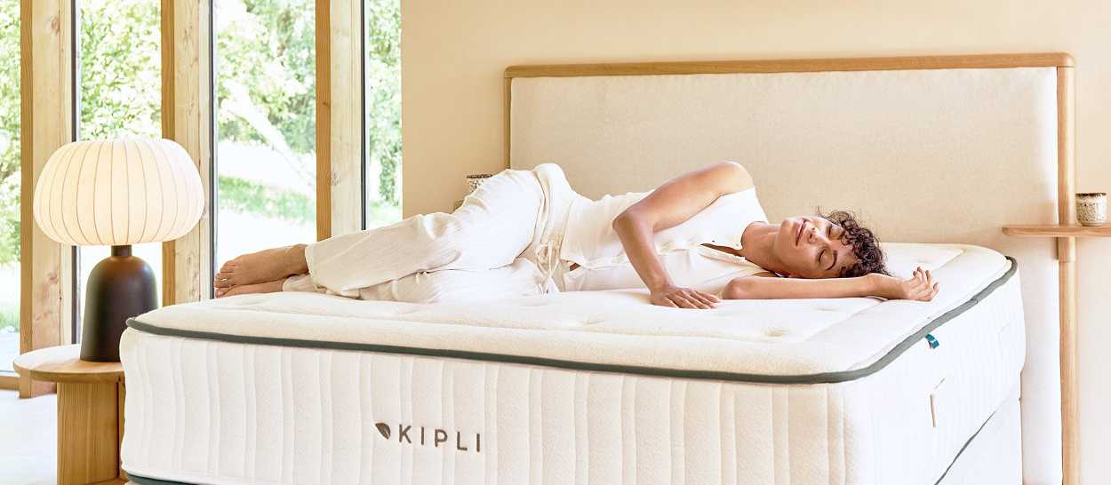 femme détendue allongée sur matelas latex naturel Kipli dans chambre lumineuse