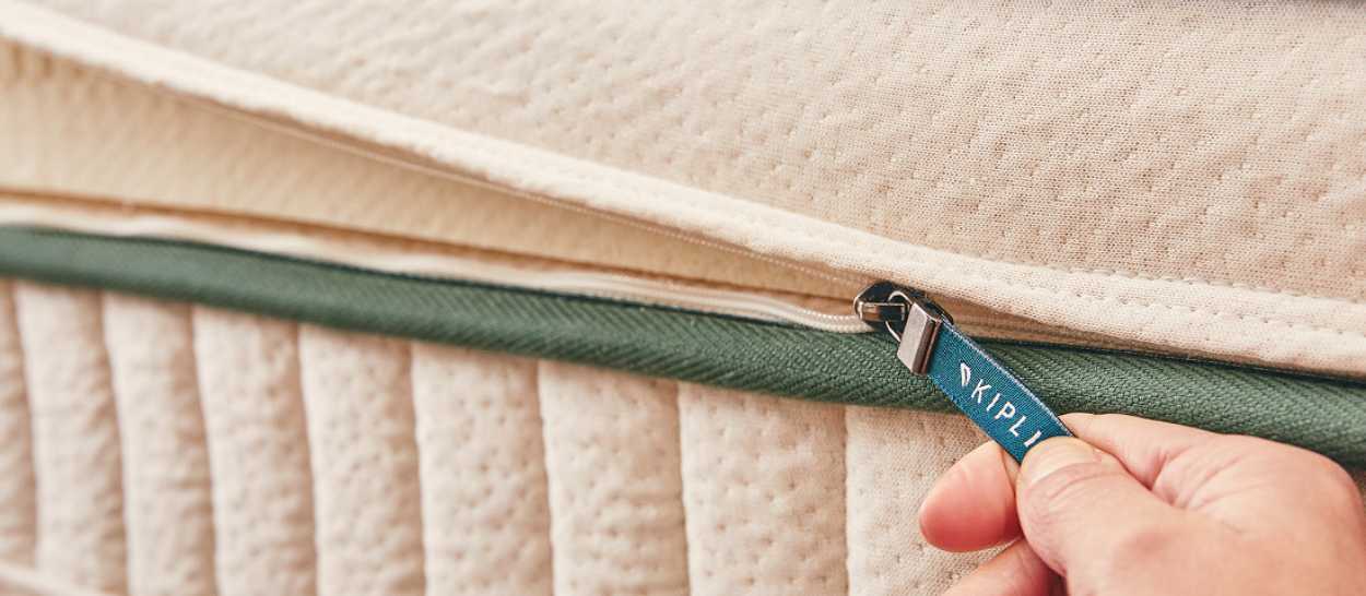 main ouvrant la housse déhoussable d’un matelas en latex naturel Kipli