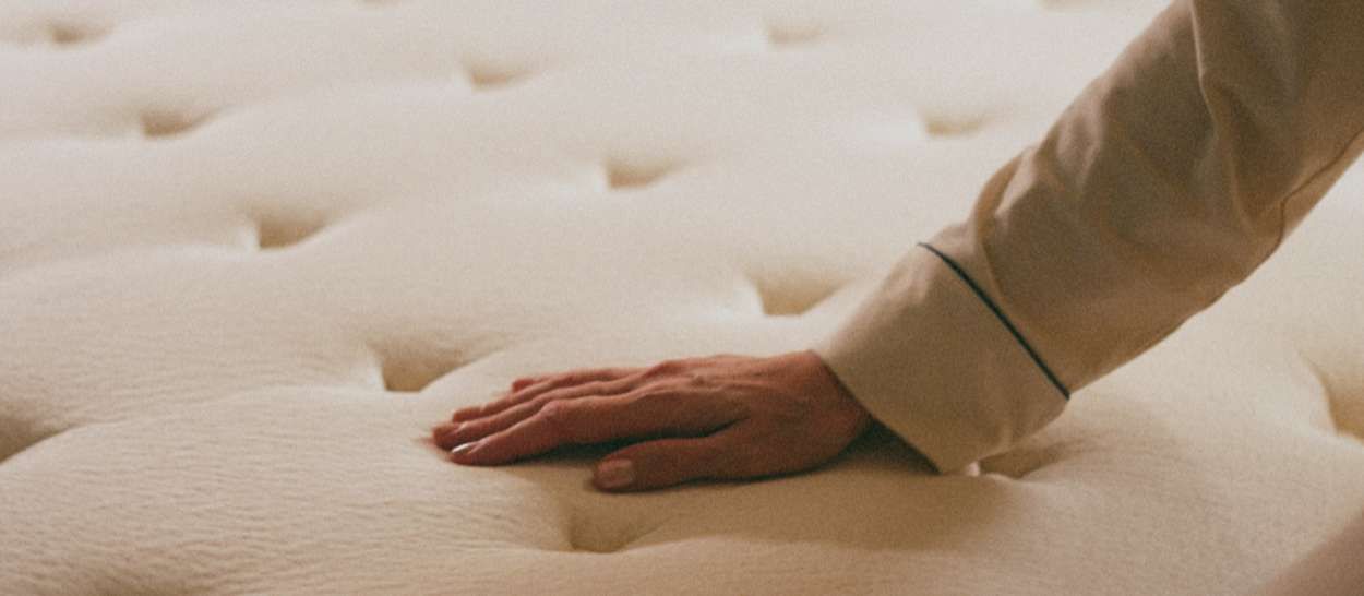 Main testant le confort d’un matelas en latex naturel Kipli à surface capitonnée