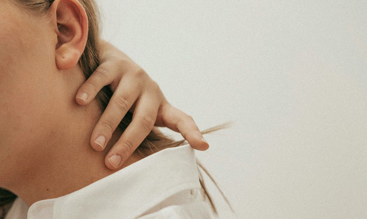main posée sur la nuque d’une femme, illustrant une douleur cervicale liée à une hernie discale