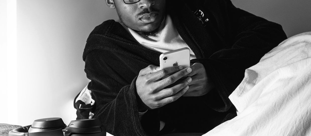 Adolescent utilisant son smartphone le soir dans son lit, illustrant l’impact des écrans, de la lumière bleue et de la stimulation numérique sur le sommeil.