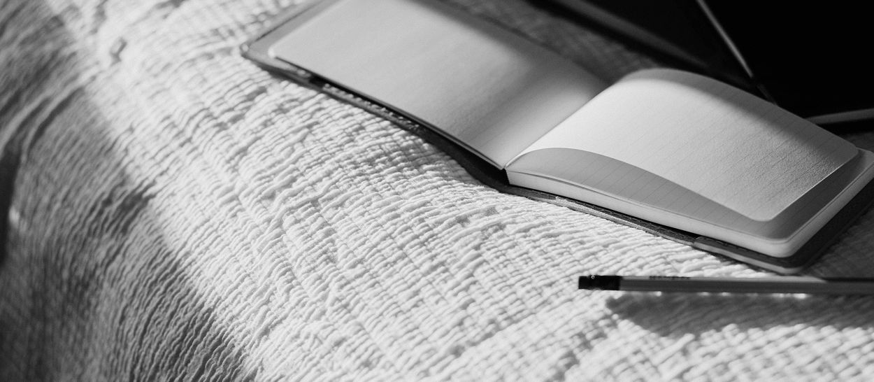 Carnet ouvert posé sur un lit, illustrant un rituel doux pour se souvenir de ses rêves au réveil et favoriser la mémoire onirique.