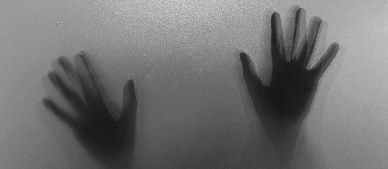 Silhouettes de mains derrière une surface translucide, illustrant l’angoisse nocturne, les cauchemars et leur lien avec le sommeil paradoxal (REM).