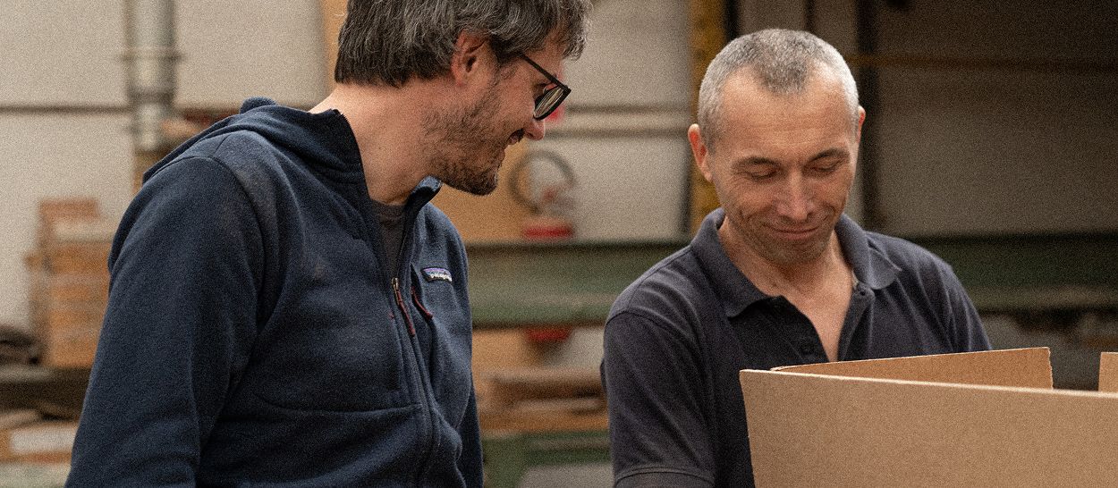 Davide, cofondateur de Kipli, échange avec un artisan dans un atelier, illustrant le savoir-faire et l’héritage autour du latex naturel.