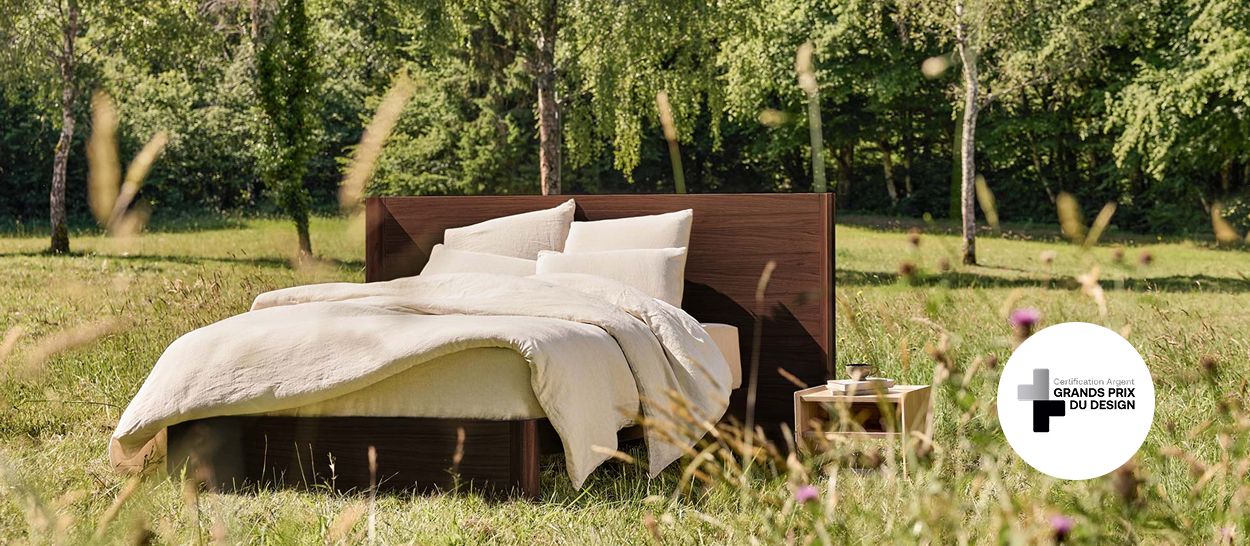 Lit en chêne massif dans une clairière, visuel de la gamme primée aux Grands Prix du Design 2025 (Lauréat Argent)