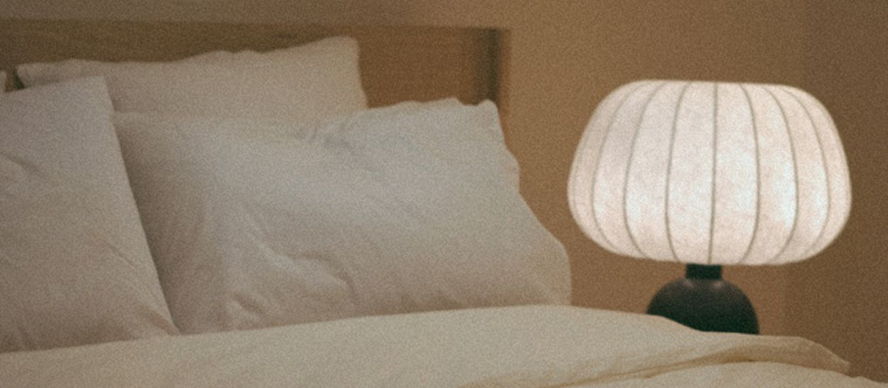 Lampe Hikari de Kipli diffusant une lumière chaude et tamisée dans une chambre, illustrant l’importance d’un éclairage doux le soir pour favoriser l’endormissement.