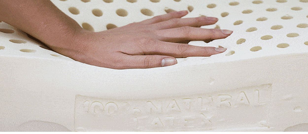 Main posée sur un matelas en latex naturel, montrant sa souplesse et sa respirabilité.
