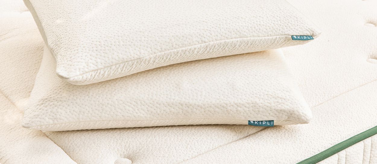 Oreillers en latex naturel Kipli empilés sur un matelas, montrant leur tenue, leur épaisseur et la housse respirante