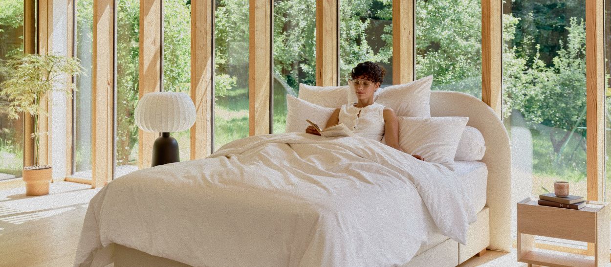 Chambre apaisée avec literie naturelle Kipli, lumière douce et environnement végétal, illustrant une vision globale du sommeil réparateur.