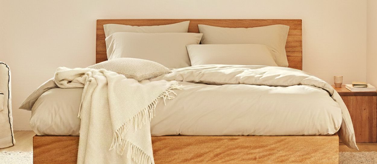 Sommier en bois massif 2 places avec tête de lit assortie dans une chambre à coucher lumineuse, illustrant l’équilibre entre dimensions, stabilité et harmonie visuelle.