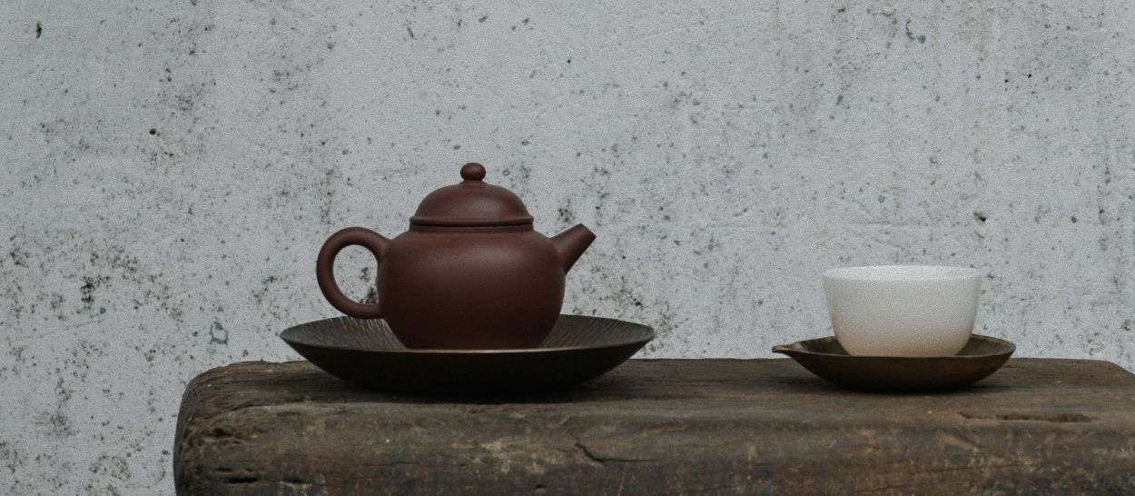 Théière et tasse posées dans un décor sobre, illustrant le rituel de la tisane du soir à base de plantes pour favoriser l’endormissement et un sommeil plus apaisé.