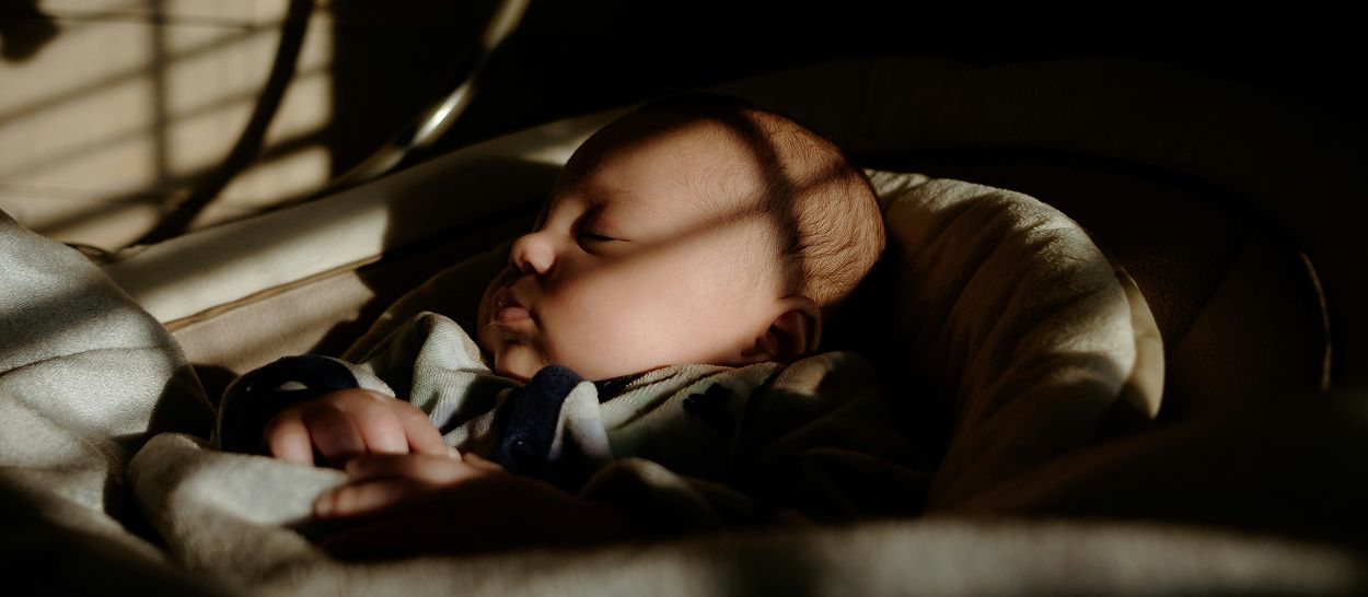 Nourrisson endormi dans son berceau, lumière filtrée par un volet, ambiance nocturne