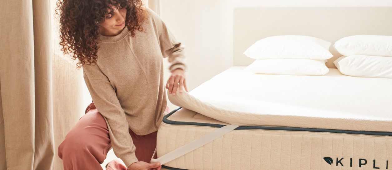 Personne installant un surmatelas naturel sur un matelas pour améliorer le confort du couchage