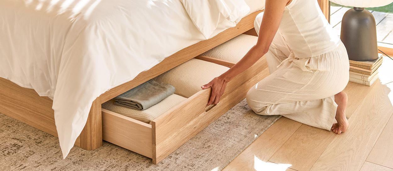 Main tirant le tiroir en chêne massif du lit NÉNUPHAR, linge de saison rangé à l'intérieur