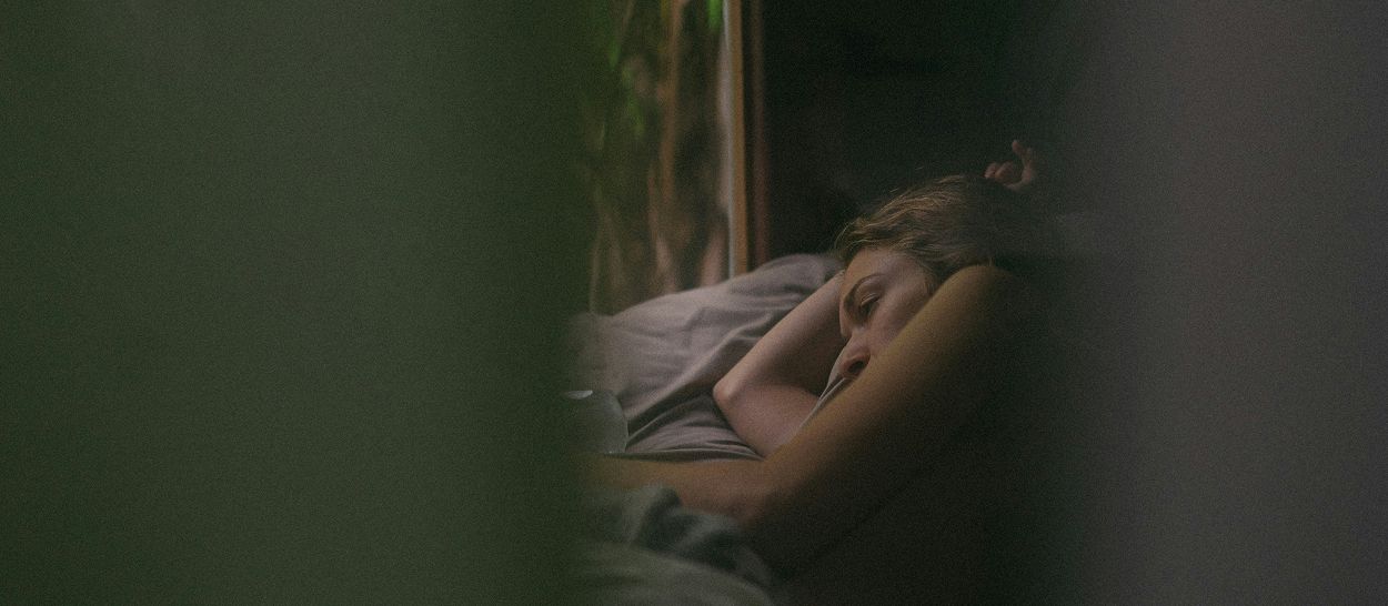 Femme réveillée dans son lit illustrant un sommeil perturbé par la chaleur excessive pendant la nuit