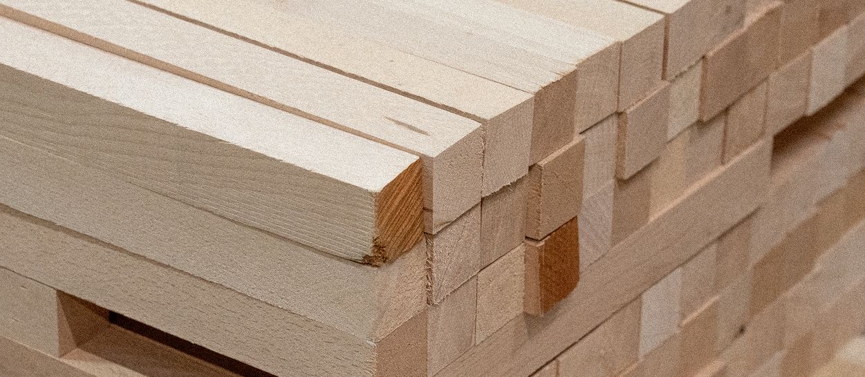 Planches de bois massif empilées en atelier, matière première pour structure de canapé