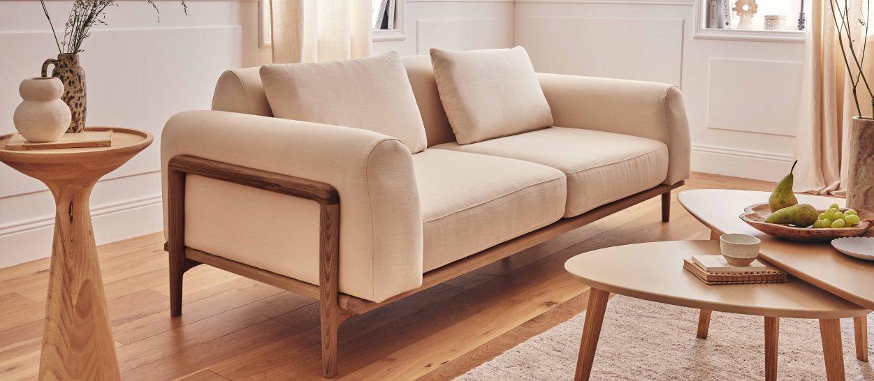 Canapé en bois massif et tissu beige dans un salon meublé, espace de circulation autour