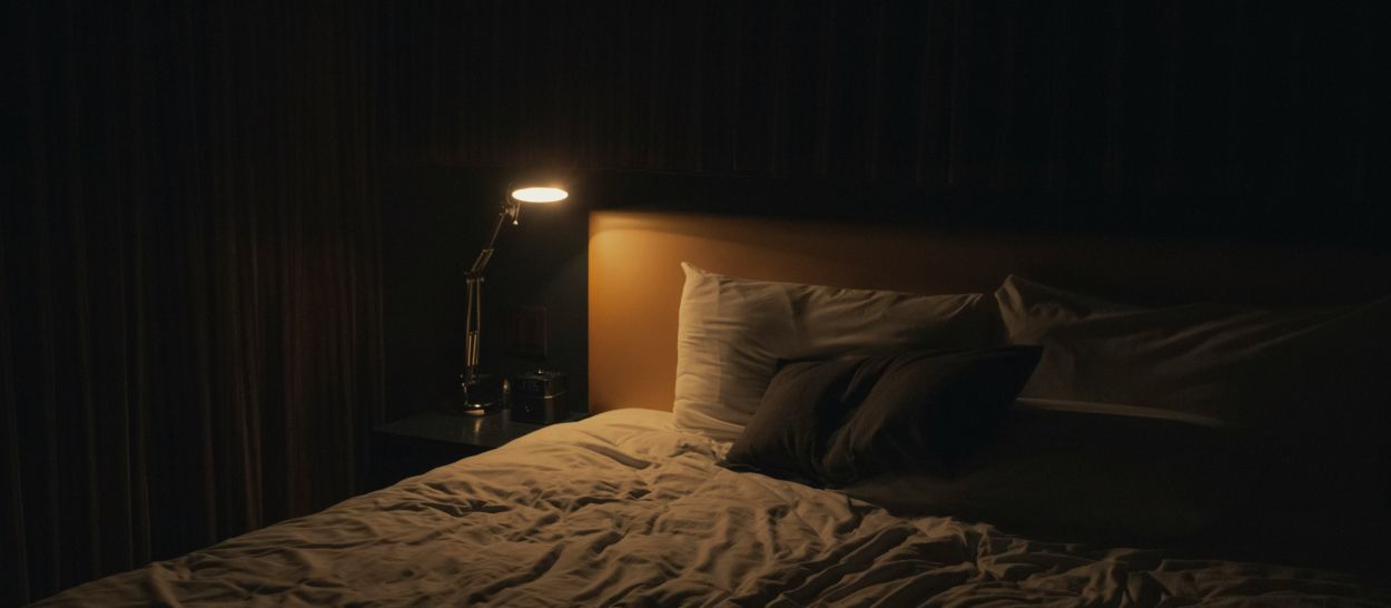 Chambre la nuit avec lampe de lecture allumée, lit blanc, obscurité totale, horloge circadienne