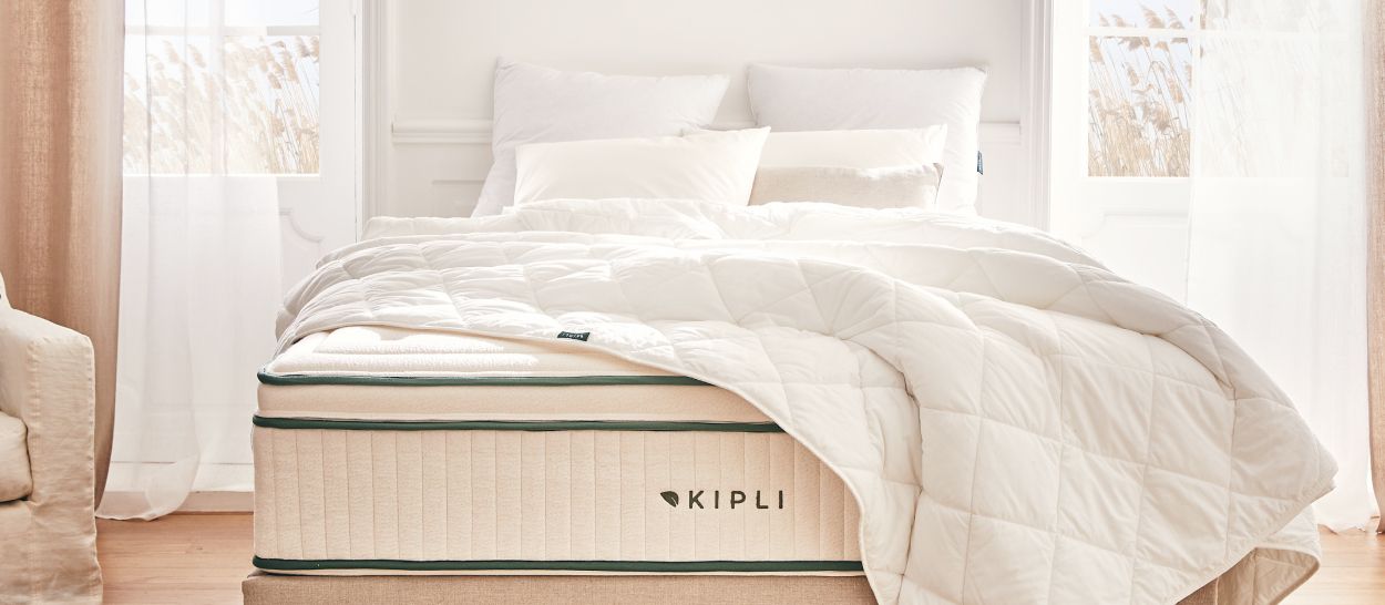 Lit double avec couette blanche généreuse, retombée visible de chaque côté du matelas Kipli