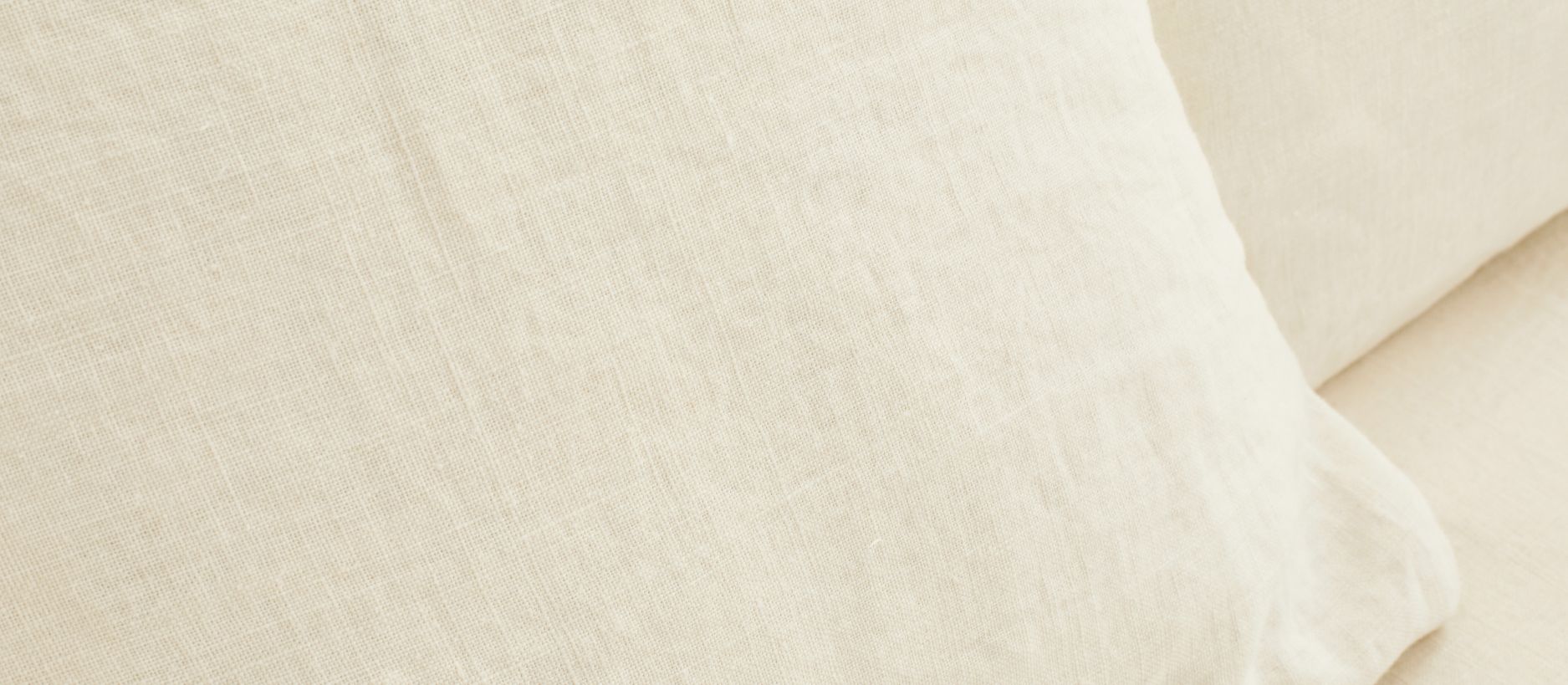 Gros plan sur le tissage d'un coussin en lin naturel écru, trame dense sans traitement chimique