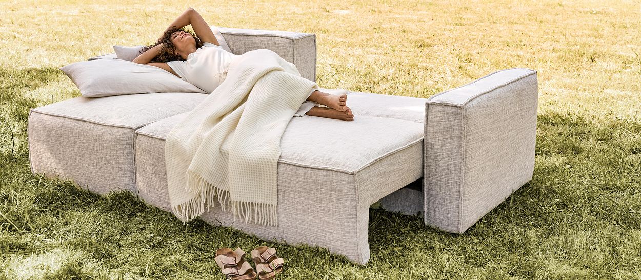 Femme allongée confortablement sur canapé convertible CLOUD en lit ouvert, couchage 140x200 cm