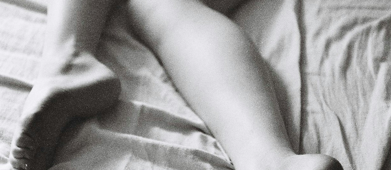 Jambes nues dans un lit aux draps froissés, crampe nocturne au mollet