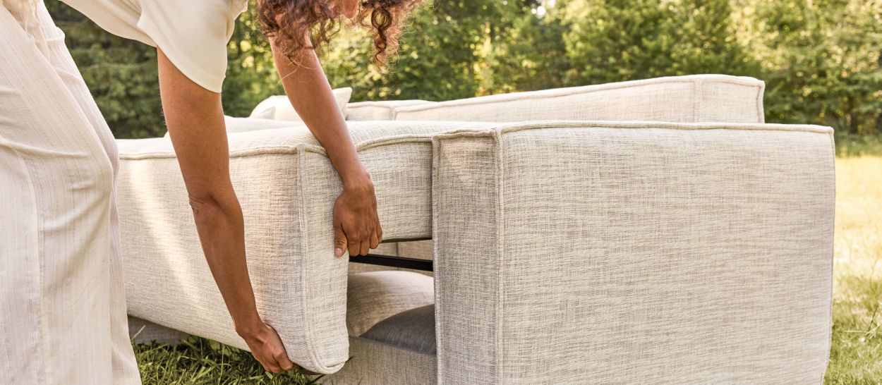 Femme actionnant le mécanisme de dossier rabattable d'un canapé convertible, déploiement fluide