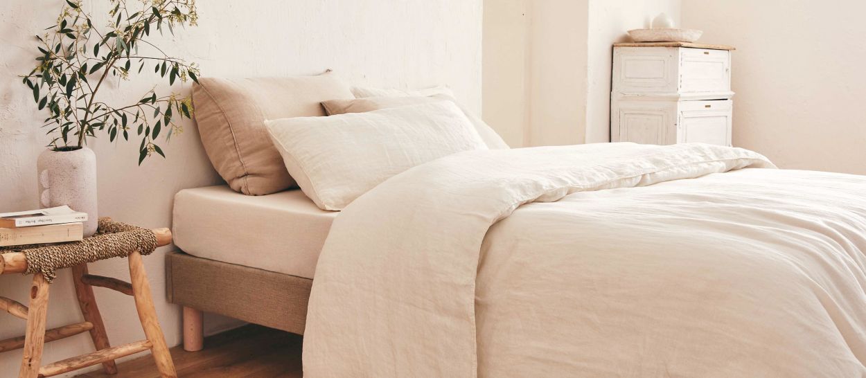 Chambre organisée, lit contre le mur, tabouret bois en chevet, espace de circulation dégagé