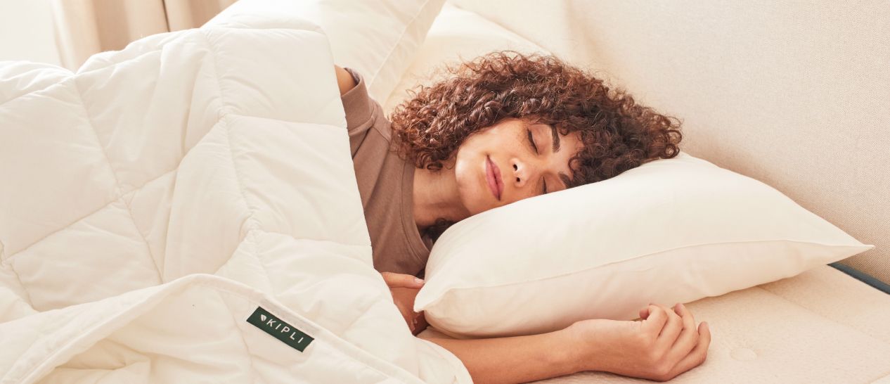 Femme endormie sous une couette blanche légère Tencel, oreiller latex naturel, sommeil paisible