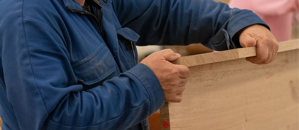 Artisan testant planche de bois massif, fabrication artisanale, contrôle qualité matériau naturel