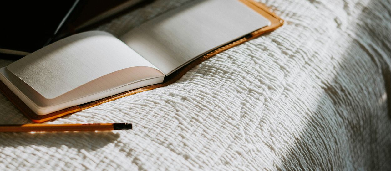 Carnet ouvert avec pages blanches sur tissu blanc pour écrire journal de rêves