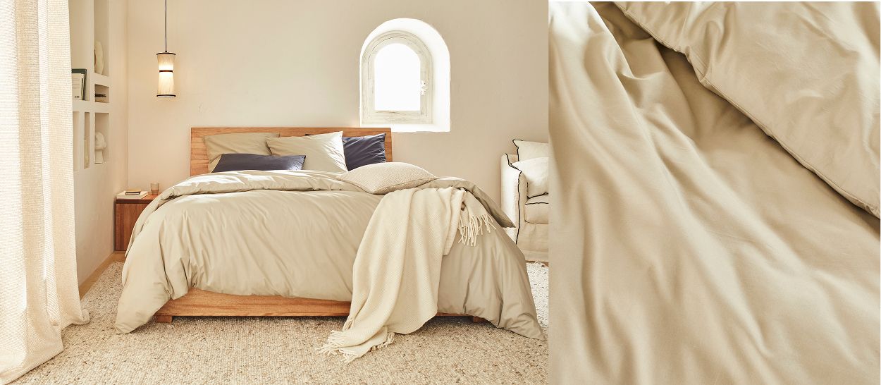 Chambre avec lit en percale coton biologique beige, draps fluides et doux, gros plan texture douce