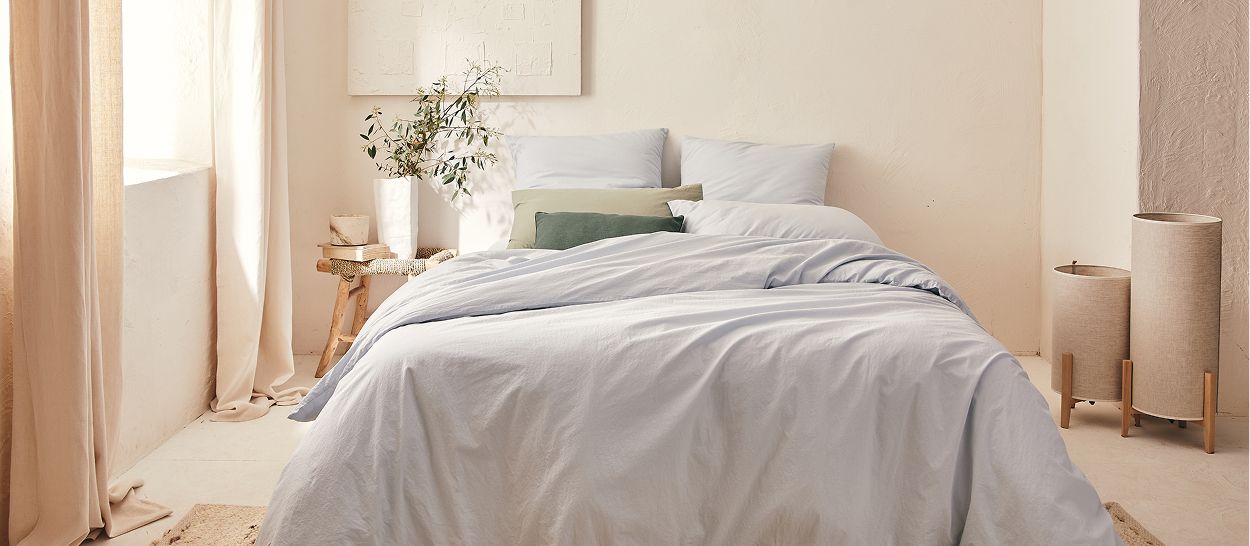 Chambre avec linge de lit bleu-gris et vert d'eau, tendances été 2026 couleurs douces et naturelles