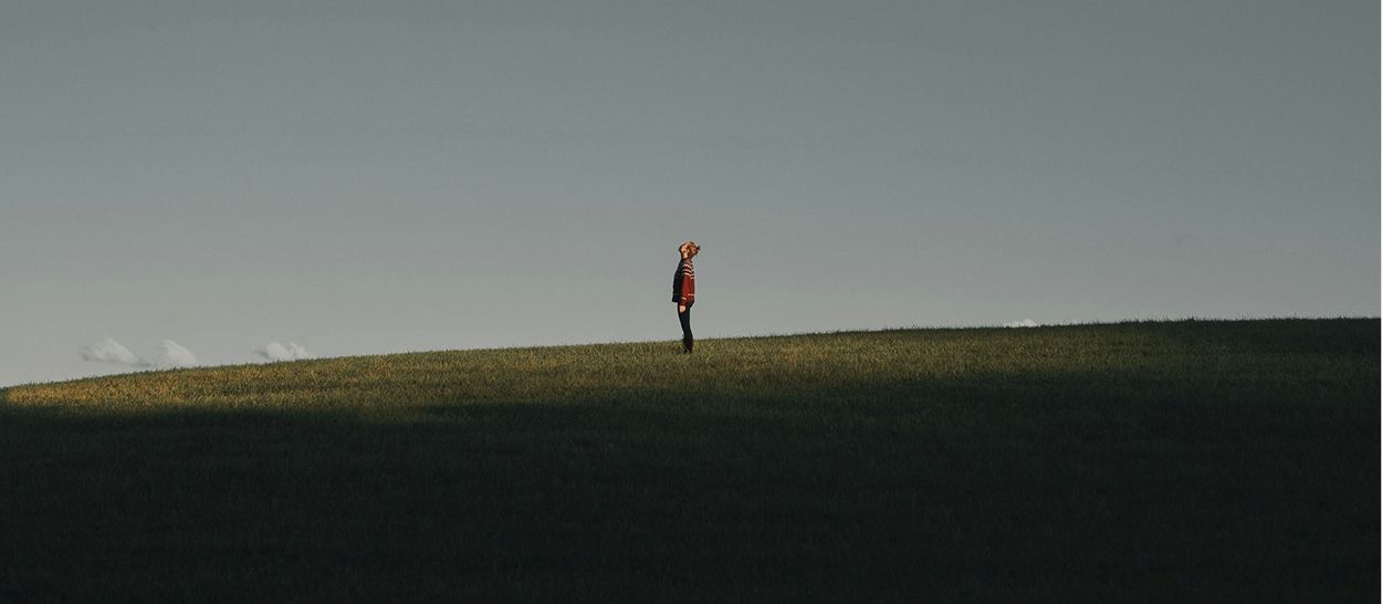 Personne seule contemple l'horizon depuis une colline dorée au coucher de soleil
