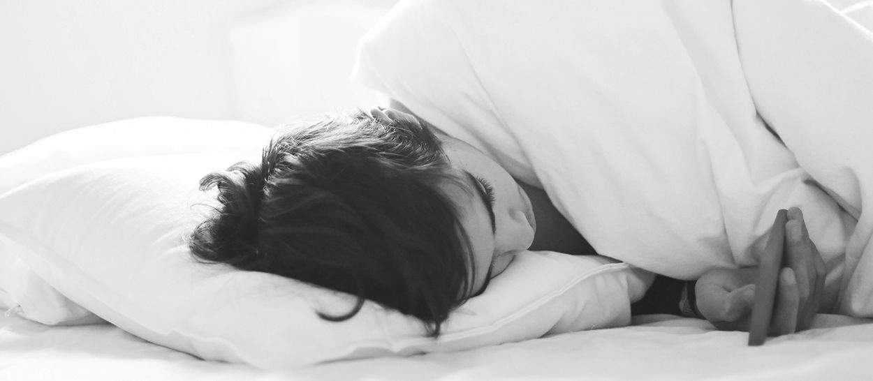 Femme endormie profondément dans lit blanc, sommeil paisible et récupération hormonale nocturne