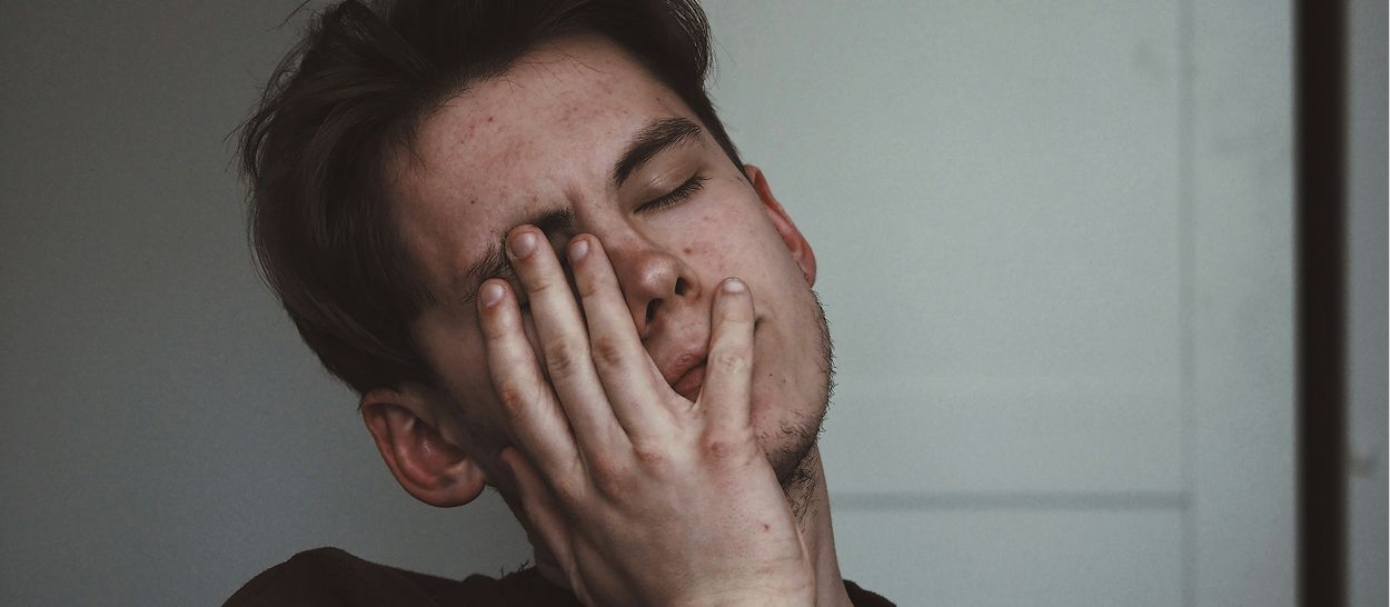 Homme stressé se tenant le visage, exprimant tension et fatigue mentale