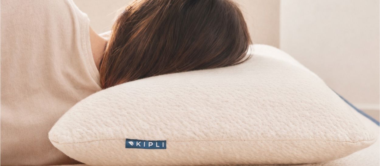 Femme dormant sur le dos avec oreiller Kipli montrant alignement cervical neutre et confort optimal