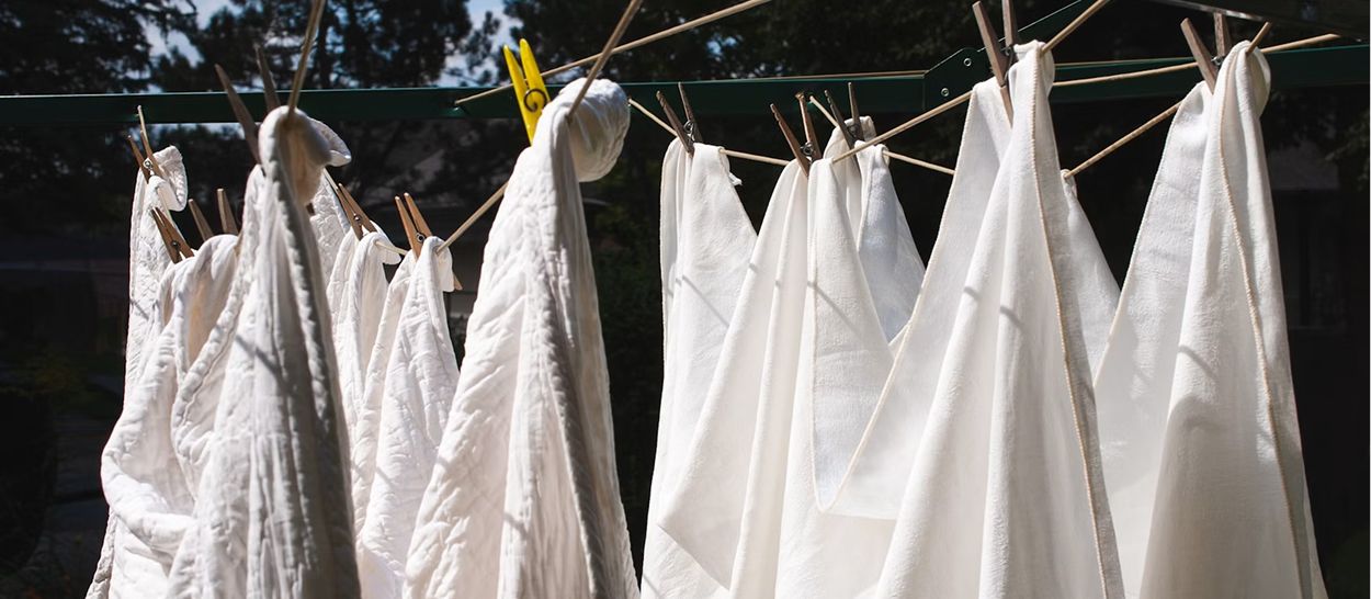 Linge blanc séchant à l'air libre au soleil illustrant entretien correct pour peaux sensibles