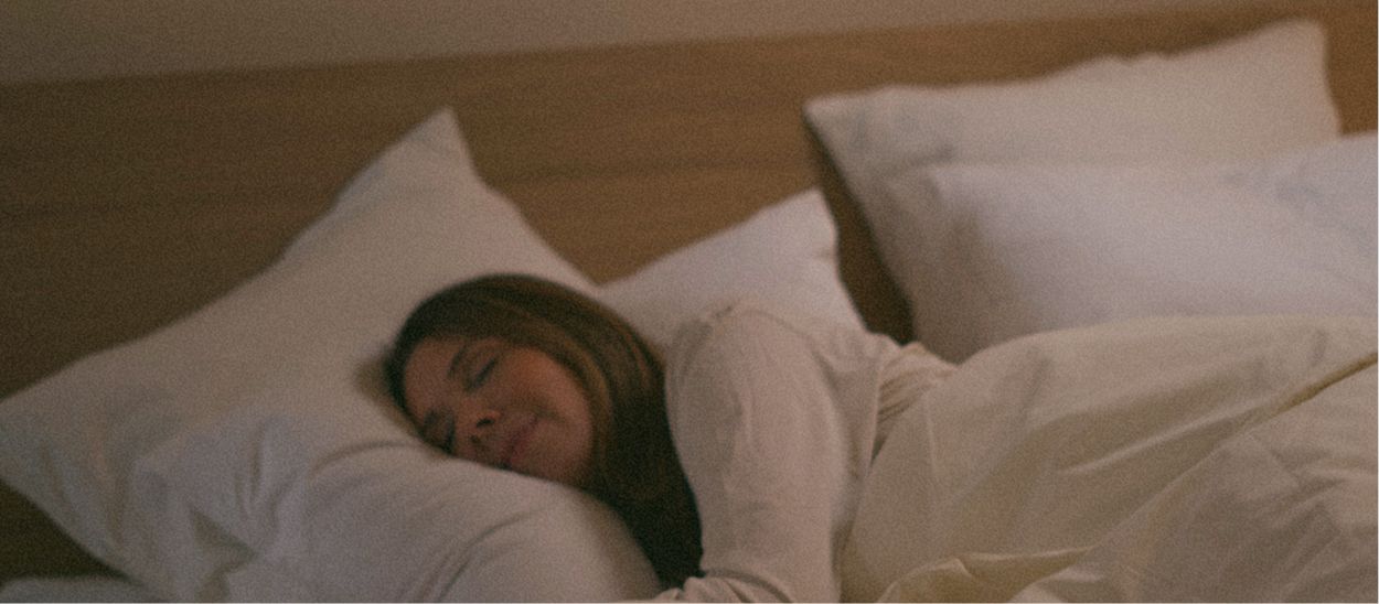 Femme dormant paisiblement sur linge blanc naturel montrant confort et qualité du sommeil avec matières respirantes